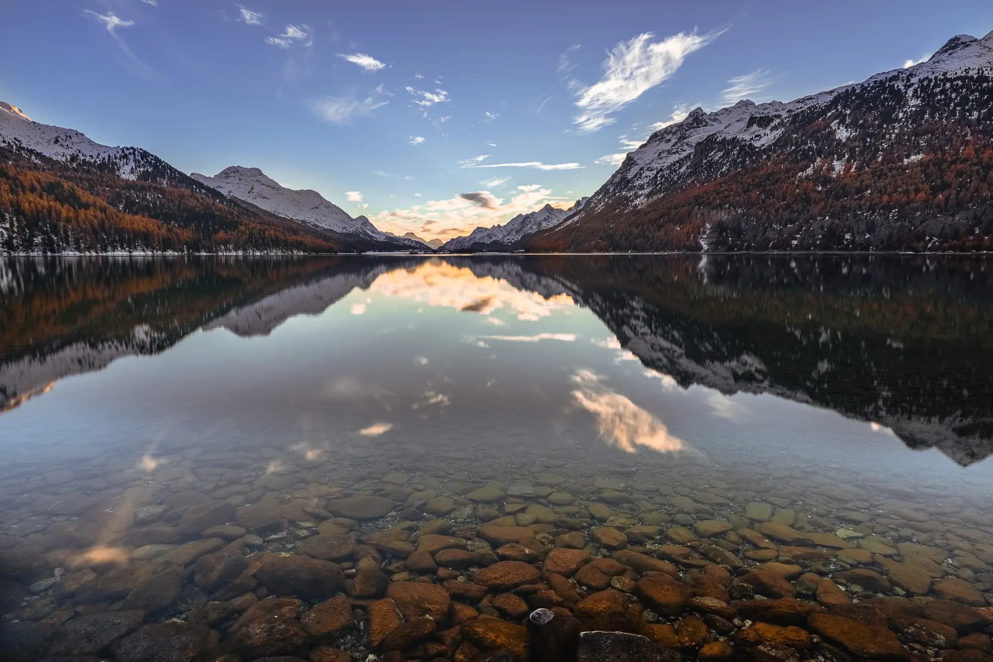An interesting foreground leads into the reflection of the Silvaplana lake, the mountain slopes are decorated with larches and the whole motif runs towards the light atmosphere at the intersection of the valley